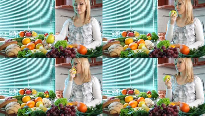 孕妇在厨房里吃很多蔬菜和水果附近的苹果