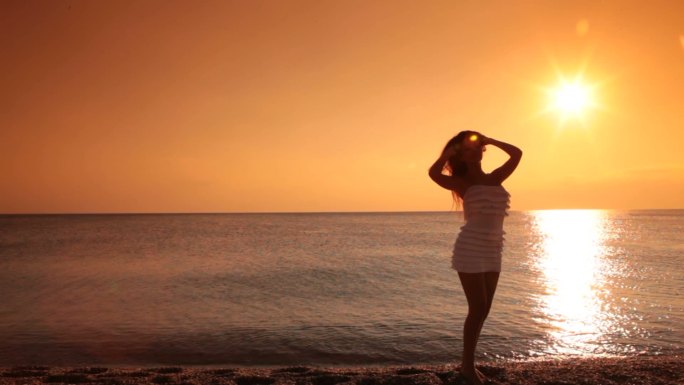 日落时一名女子在海滩上的剪影