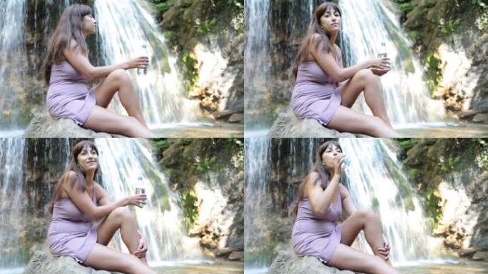 坐在瀑布边喝水的年轻女子