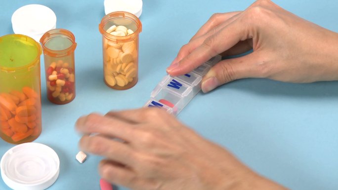 女人把药片分到一个塑料容器里女人把药片分到一个塑料容器里