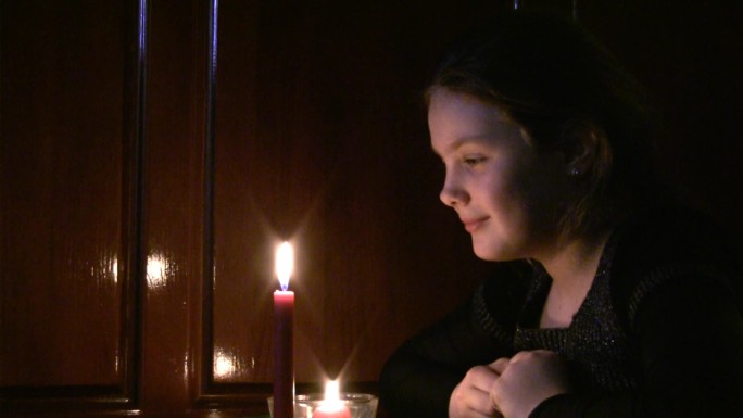 少女看着燃烧的蜡烛。