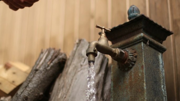 旧水龙头滴水。铁喷泉。一个人打开和关闭水龙头。生态、节能、可持续发展、水资源浪费、家庭经济或省钱想法