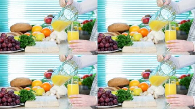 女性在厨房附近用手浇橙汁，里面有很多蔬菜和水果