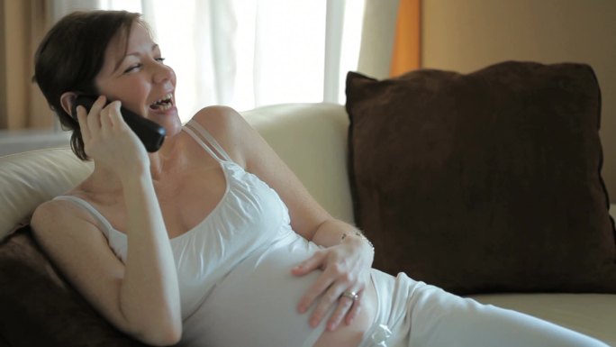 意大利孕妇坐在沙发上讲电话