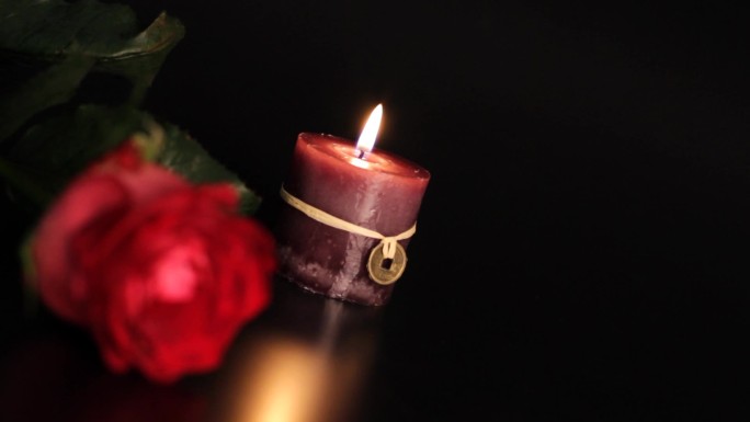 黑色背景上的红玫瑰和蜡烛。