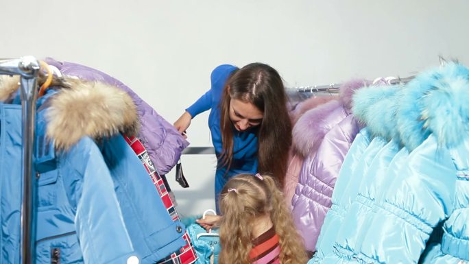 母亲和女儿在服装店买冬衣，试着穿羽绒被