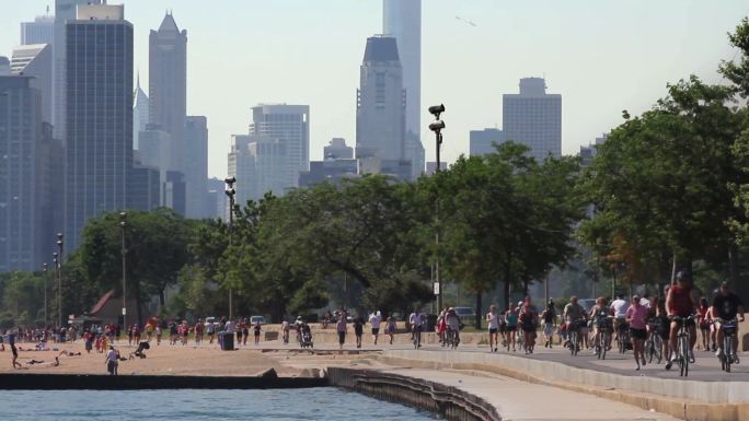 以芝加哥天际线为背景的湖岸小道上的跑步者和自行车手
