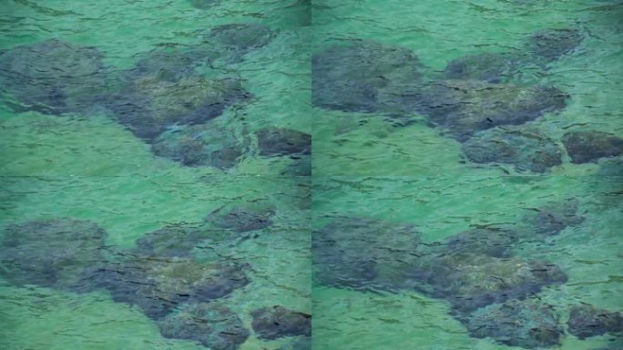 绿松石色的海水覆盖着海岸附近的一排岩石。