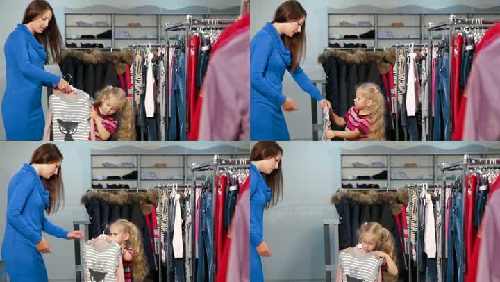 母亲和女儿在服装店买女孩的衣服，有趣的小女孩正在试穿束腰毛衣