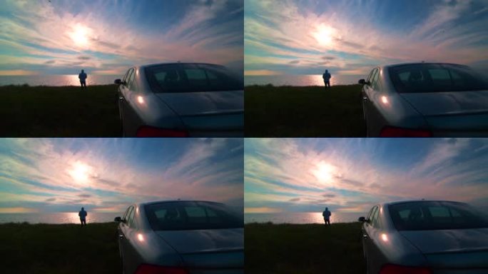 一个女人的剪影在他的车旁欣赏日落时的海岸风光