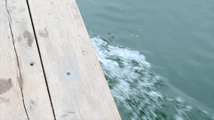 阳光下桂林青狮潭水上行驶的木船激起的浪花