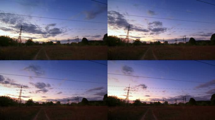 在一片平坦的风景和落日中，电线的轮廓。时间点。