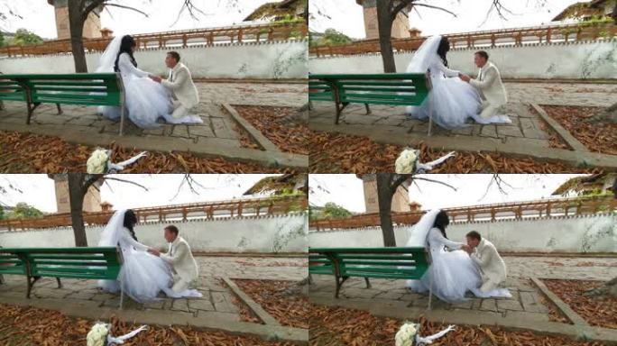 新婚夫妇坐在秋天公园的长椅上