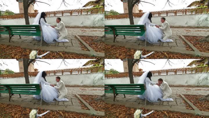 新婚夫妇坐在秋天公园的长椅上