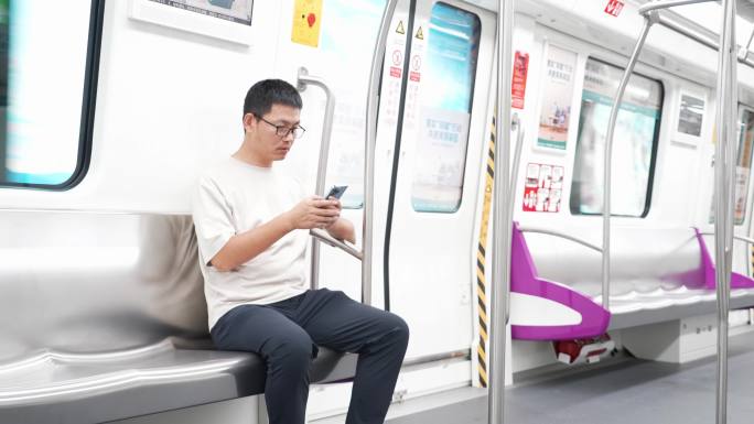 男子在地铁座位上用手机玩手机