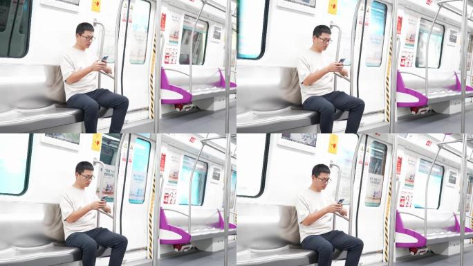 男子在地铁座位上用手机玩手机