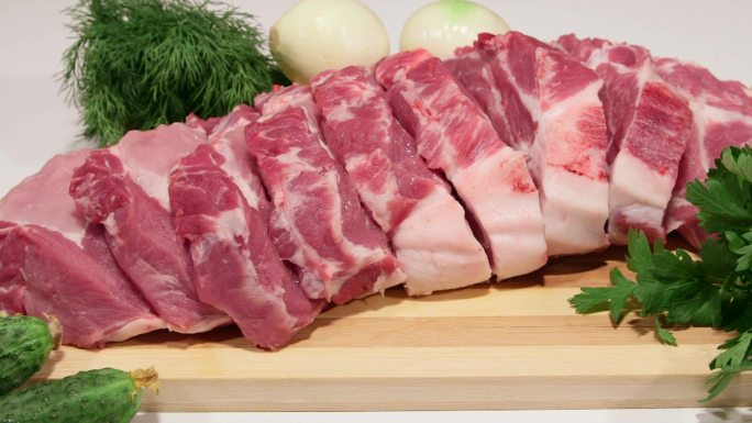 将新鲜猪肉和蔬菜切成薄片放在木制砧板上，特写多莉镜头
