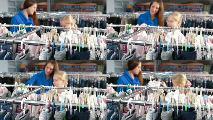 母亲和女儿在服装店买女孩的衣服，关注前景