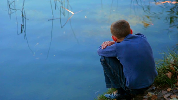坐在湖边思考的男孩