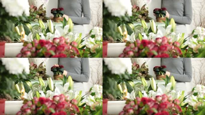 花店里摆满了鲜花，背景是女人在布置情人节玫瑰心花束