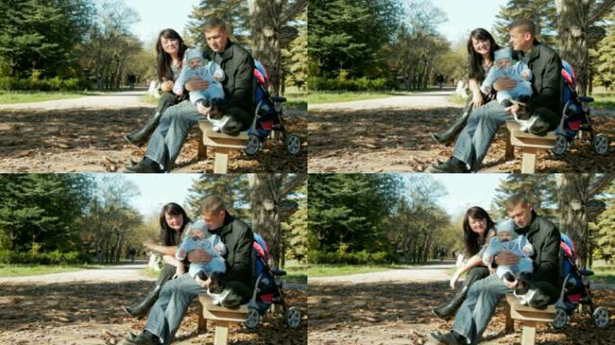 一个快乐的家庭，一个蹒跚学步的孩子和一只宠物在公园的长椅上休息