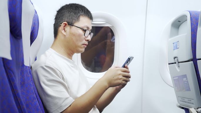 男子在飞机上用手机刷视频