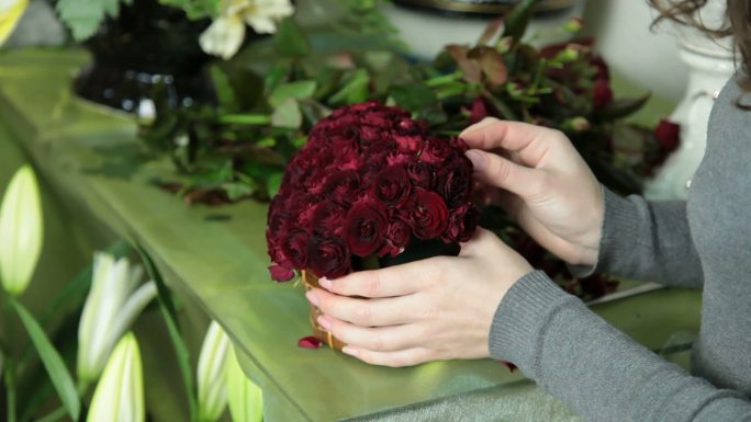 女花商在花店特写镜头中安排情人节玫瑰心花束