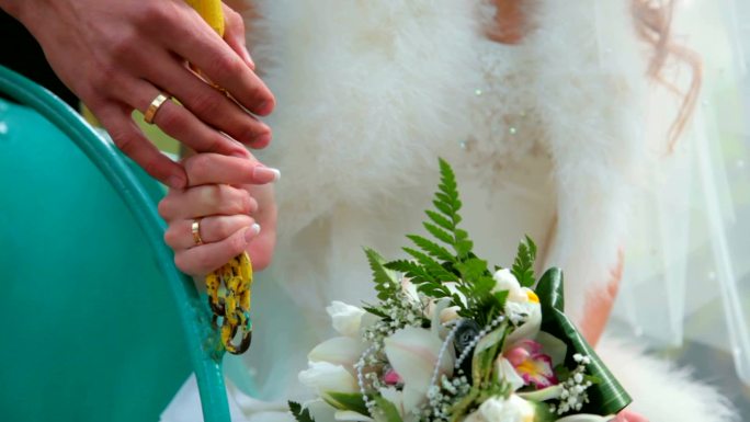 新娘和新郎手牵着手，戴着结婚戒指