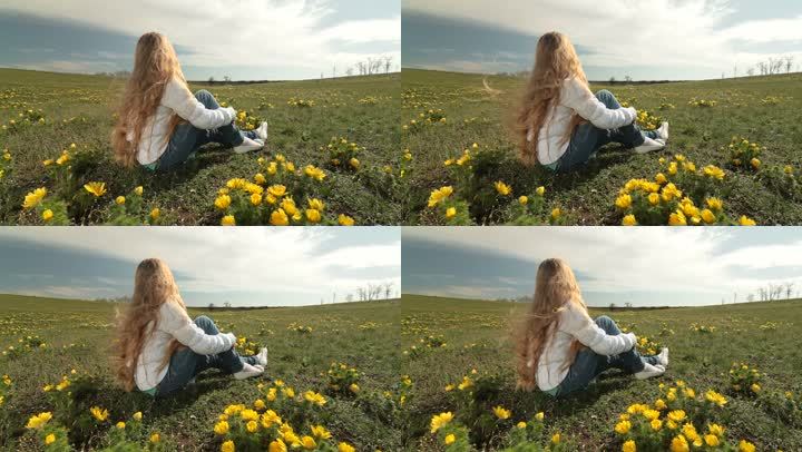 金发碧眼的小女孩坐在春天的野黄色牡丹草地上