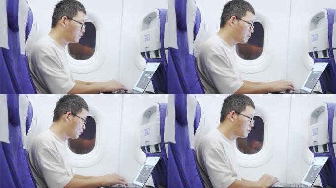 男子在飞机上使用笔记本电脑