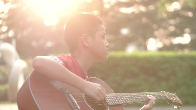 唯美夕阳下在小区草地上弹吉他的孩子