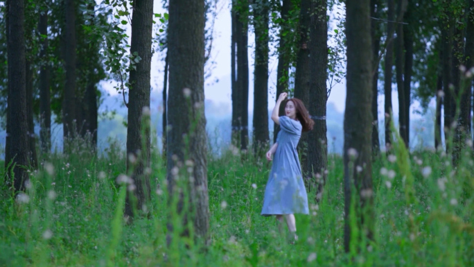 年轻女子在草地树林中奔跑跳舞