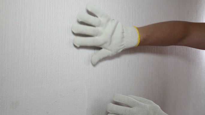 戴手套的男人展示如何移除旧墙纸