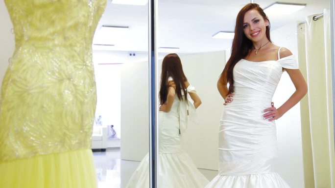 年轻迷人的女人在婚纱店挑选结婚鞋，摆姿势，看着摄像机
