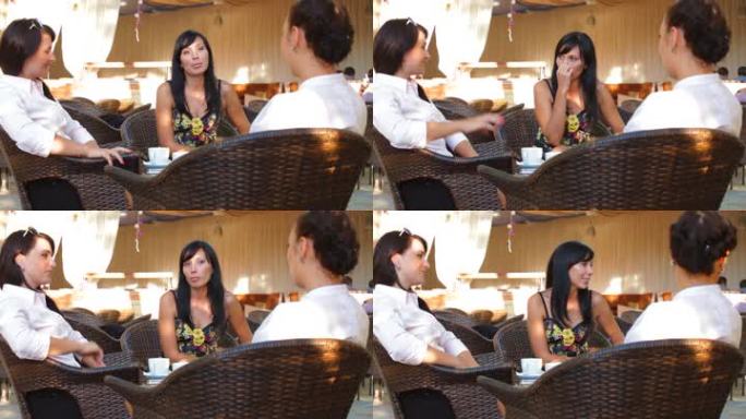 三个女人在户外咖啡馆边喝咖啡边分享故事