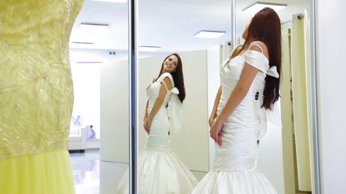 年轻迷人的新娘在婚纱店试穿婚纱
