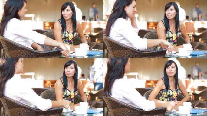 两个女人在户外咖啡馆边喝咖啡边分享故事