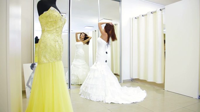 年轻迷人的女人在新娘精品店选择婚纱