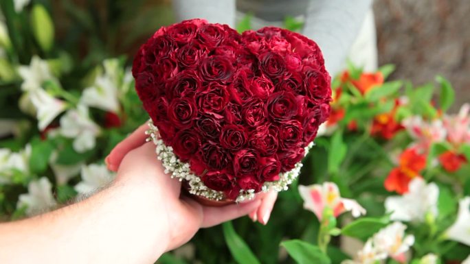 没有什么比心和玫瑰更能表达我爱你了。情人节男女手拿玫瑰心花束。