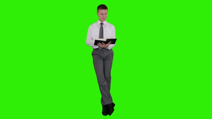 年轻的商人看书，坐在绿色的屏幕上