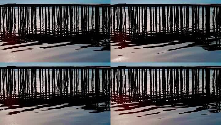 波光粼粼的湖面和木柱的轮廓，形成垂直线的图案