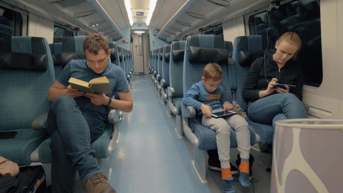 一家三口在深夜乘特快列车旅行。妈妈和儿子忙于手机和平板电脑，而爸爸更喜欢看书