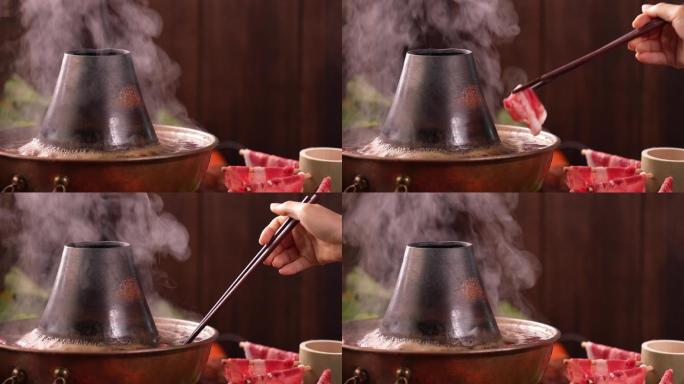 往沸腾的涮肉火锅里夹肉
