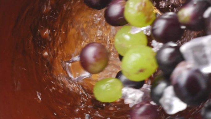葡萄和冰块掉入转动的葡萄汁 红酒中