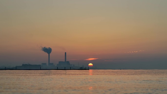 太阳从海平面升起，海边工厂日出美景