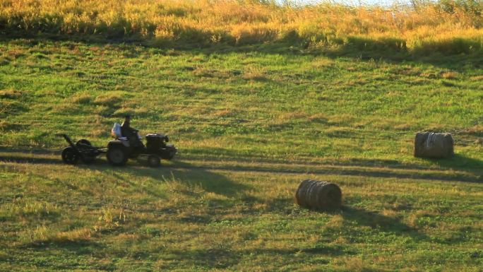 农民驾驶拖拉机收割牧草