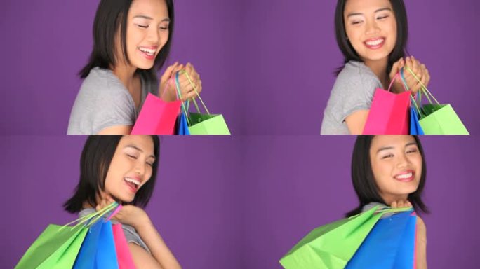 微笑的年轻女子肩上扛着购物袋