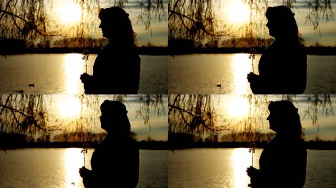夕阳下清澈的湖边，美丽的女士带着花的剪影