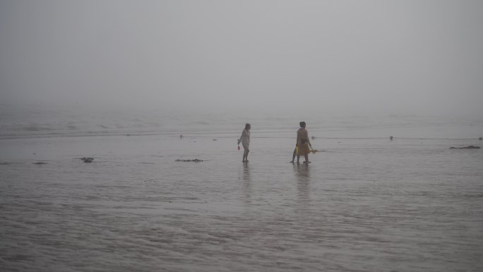 游客海边赶海阴雨天雾天阴天大海沙滩挖海鲜