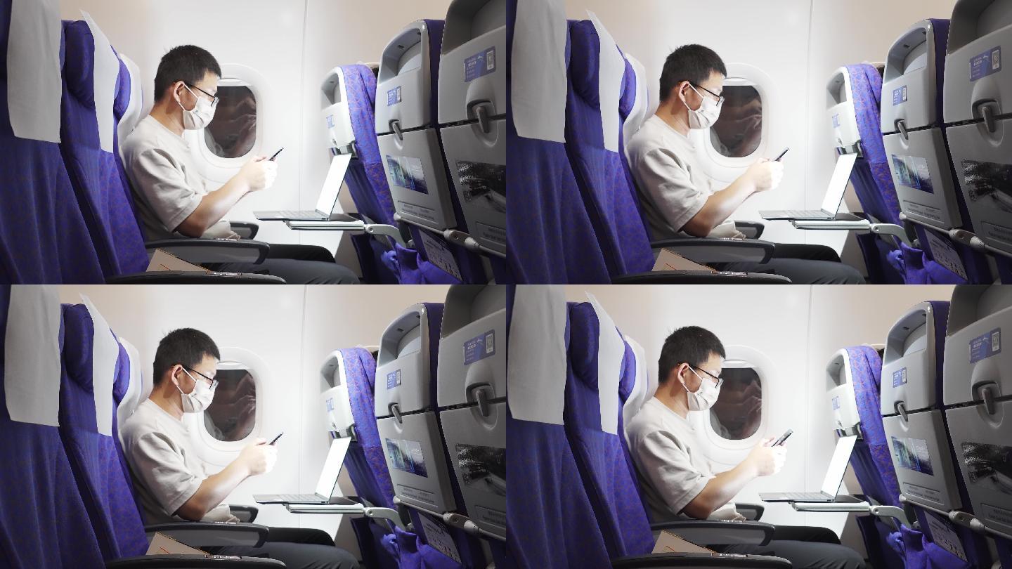 疫情期间男子在飞机上使用手机和笔记本电脑